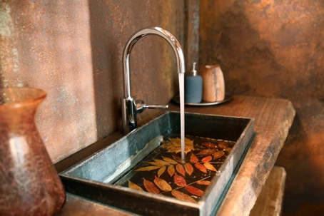 Faucet running as fall leaves float in sink