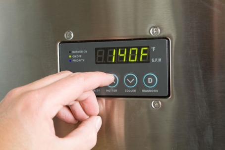 Person adjusting temperature on a hot water heater